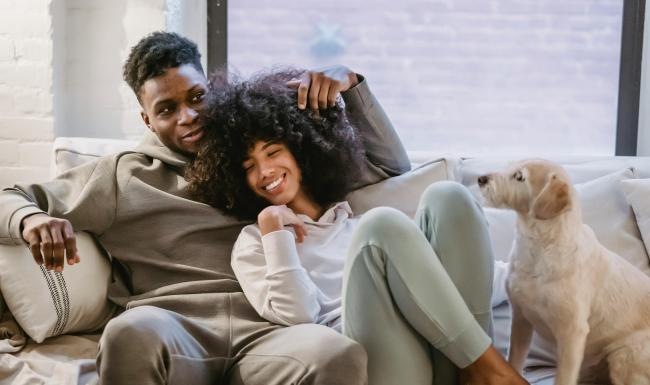 a man and woman sitting on a couch with a dog